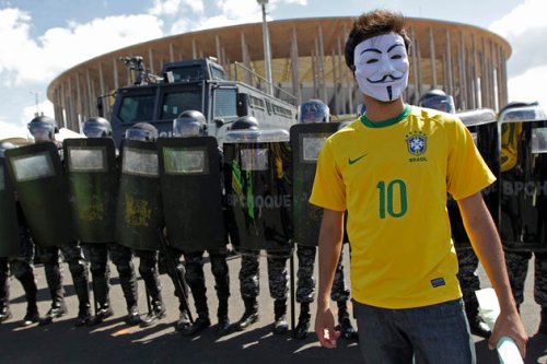 An activist demonstrates in front of riot police outside the Mane Garrincha National Stadium in Brasilia